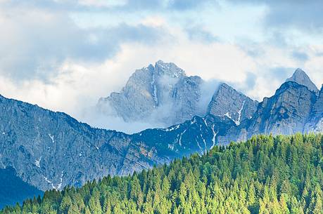 The mount Sernio emerges from the clouds and stands with majesty abiove the green woods