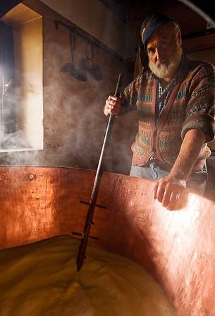 In the dairy of malga Ielma the dairyman making cheese and butter sa once again, warming the milk with the fire of wood In the dairy of malga Ielma the dairyman making cheese and butter sa once again, warming the milk with the fire of wood