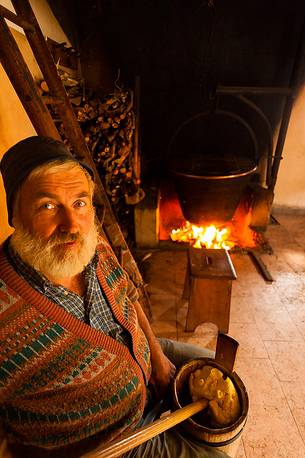 In the dairy of malga Ielma the dairyman making cheese and butter sa once again, warming the milk with the fire of wood In the dairy of malga Ielma the dairyman making cheese and butter sa once again, warming the milk with the fire of wood
