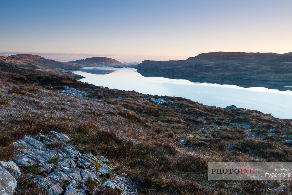 Dawn over frost covered meadows looking out over the waters of Loch Rog Beag near Giosla in the Outer Hebrides on the Isle of Harris, Scotland.