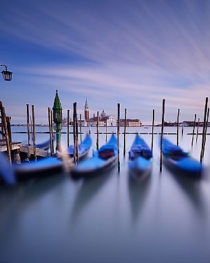 A colorful sunset in the magic mood of Venice with the traditional gondolas in the flow of time, San Giorgio Maggiore church in the background, Venice, Italy