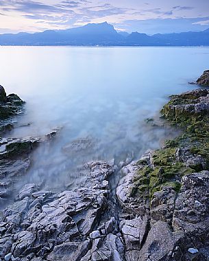 A coastal view at summer sunset from Baia delle Sirene on the eastern coast of Garda Lake, in the background the Mount Pizzocolo, Verona, Veneto, Italy, Europe