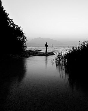 Alone people in silhouette looking the Garda lake at surrise, in the background the Mount Baldo, Sirmoione, Garda lake, Brescia, Lombary, Italy, Europe