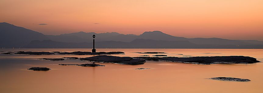 Garda lake form Sirmione village at sunset, in the background the silhouettes of Mount Baldo and Mount Pastello, Brescia, Lombardy, Italy, Europe