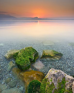 Garda lake at sunrise form Sirmione, in the background the silhouettes of Mount Baldo and Mount Pastello, Brescia, Lombardy, Italy, Europe