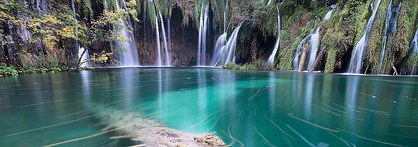 An intimate panoramic vision of a waterfall and lake in the the colorful autumn forest in the Plitvice national park, Dalmatia, Croatia, Europe