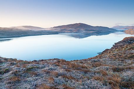 Dawn over frost covered meadows looking out over the waters of Loch Rog Beag near Giosla in the Outer Hebrides on the Isle of Harris, Scotland.