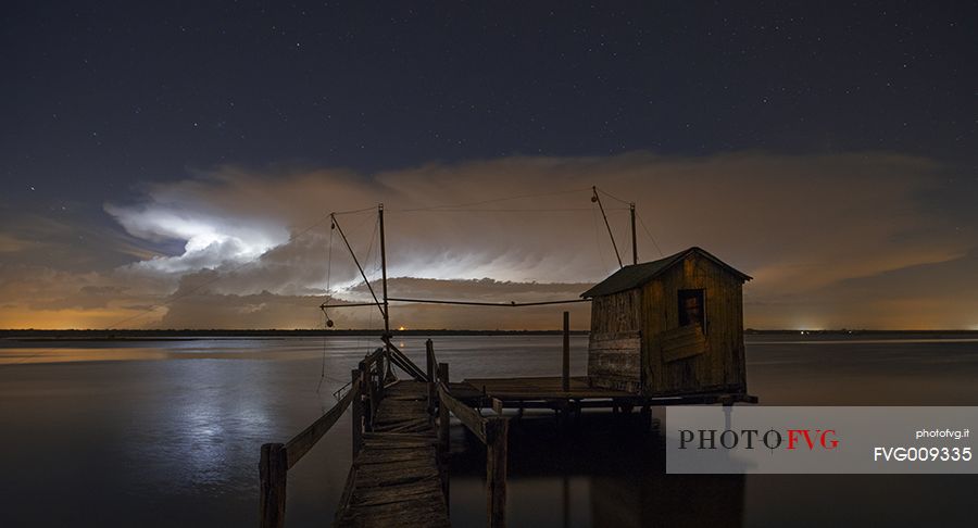night bolt on salt lake in Ravenna whit pier, boat and fishing huts