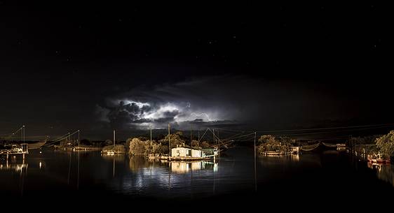 night bolt on salt lake in Ravenna whit pier, boat and fishing huts