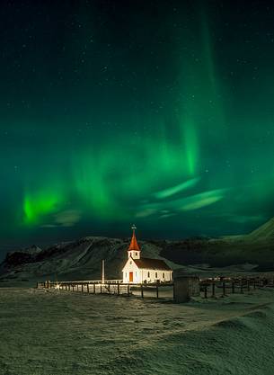 Northern lights over the church of the small village of Vik at night with 