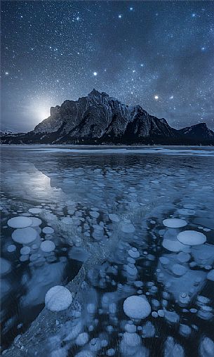 Starry night over Abraham lake with icy bubbles, Canadian Rockies landscape, Banff national park, Alberta, Canada