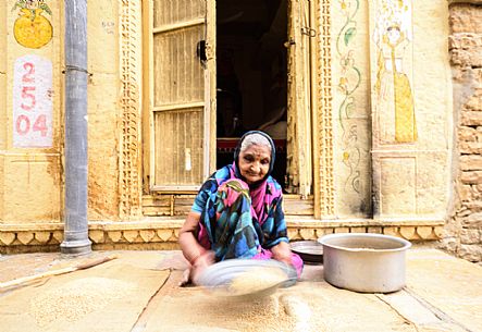 Old woman sift the flour in Jaisalmer, Rajasthan, India