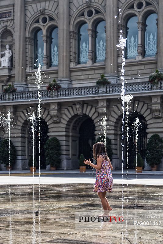 Child playing in the fountain in front of the parliament building in Bern, Switzerland, Europe