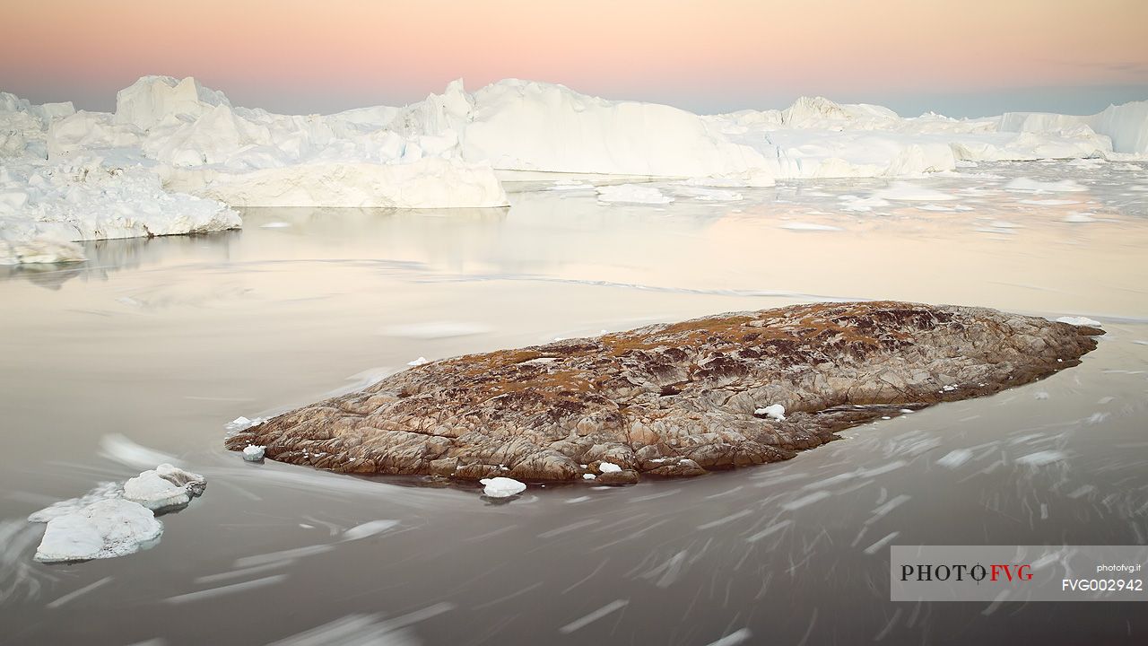 Moving ice in the water of Illulissat Fjord with the first morning light