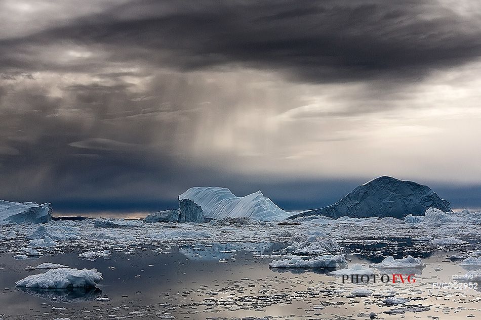 Dark clouds above blue icebergs in Disko Bay