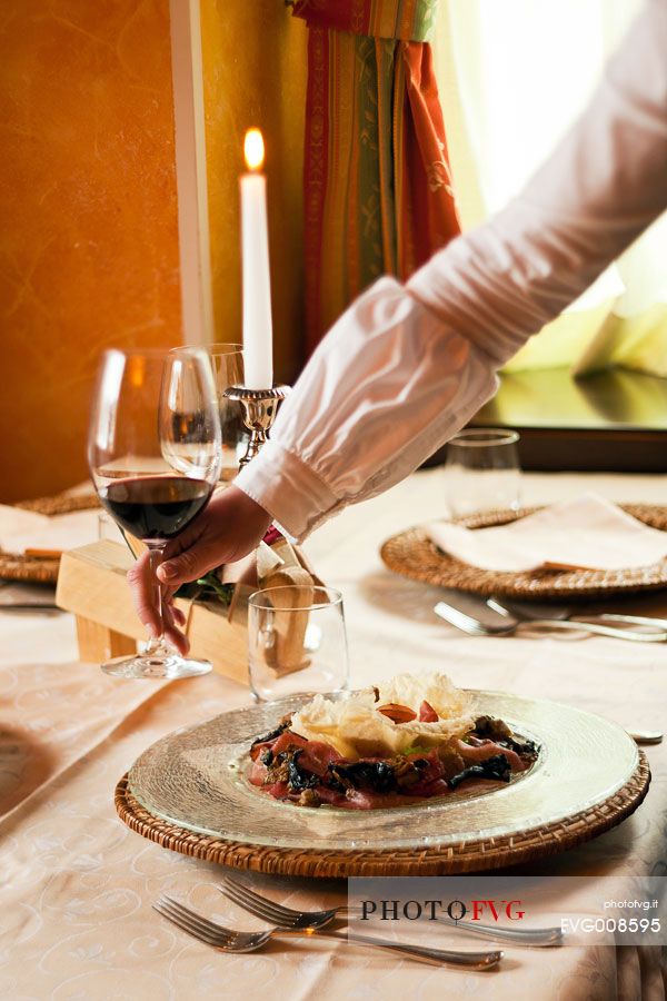 A waitress serving at the table in a typical Alpine restaurant in Sauris di Sotto