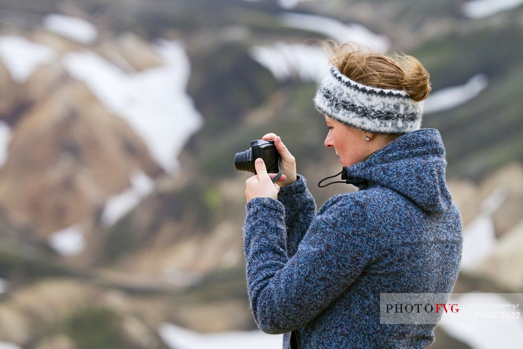 Young girl takes photos in the multicoloured rhyolite mountain area of Landmannalaugar