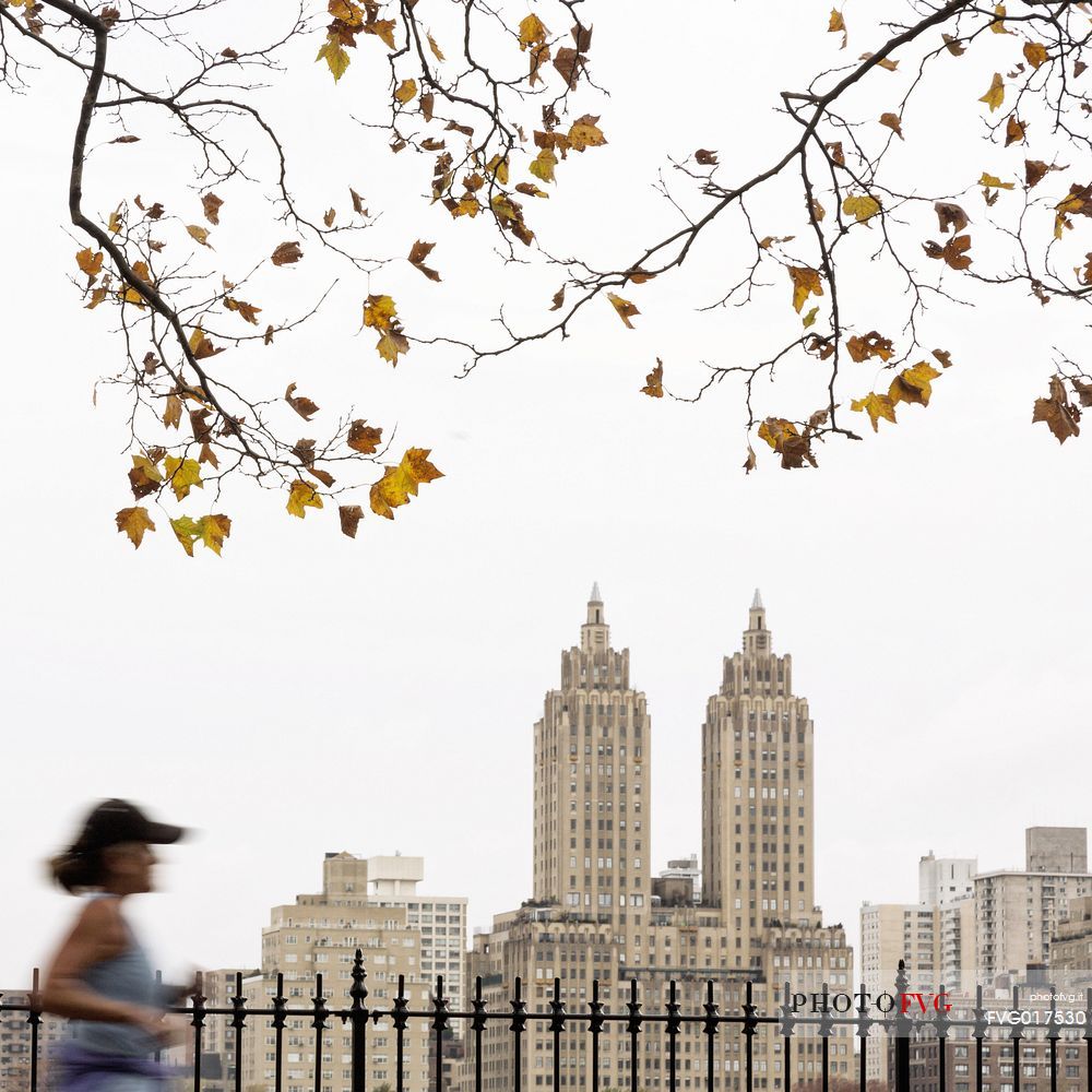 Woman running by the Jaqueline Kennedy Onassis Reservoir with El Dorado Apartments building in the background