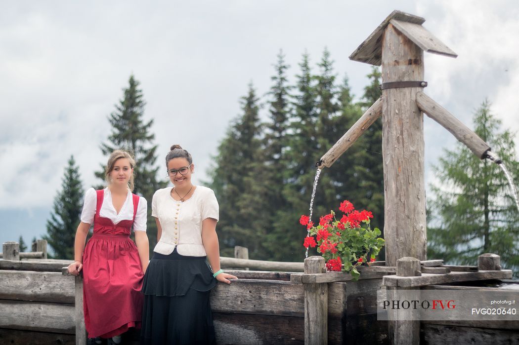 Smiling girls with a traditional dress at Rinfreddo hut, Comelico, dolomites, Italy