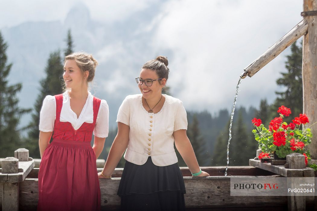 Smiling girls with a traditional dress at Rinfreddo hut, Comelico, dolomites, Italy