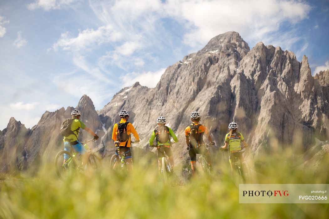 A young mountain bikers rest at Biscia summit, in the background the Sesto Dolomites, Cadore, Italy
