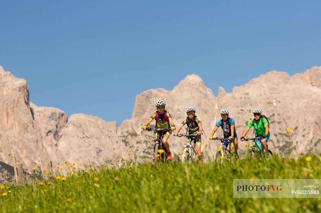 Mountain bikers at Casamazzagno, in the background the Domomites of Sesto and the Popera, Comelico, Italy