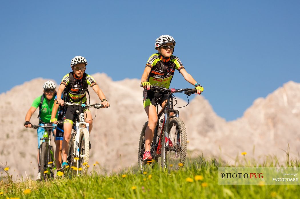 Mountain bikers at Casamazzagno, in the background the Domomites of Sesto and the Popera, Comelico, Italy