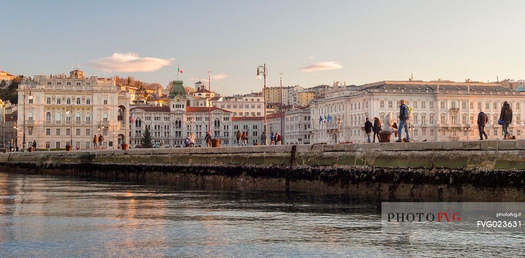 People are walking at Molo Audace, in background Piazza Unit d'Italia, view from the sea of Trieste, Italy