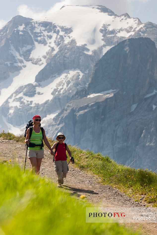 Hikers along the Viel del Pan path, in the background the Marmolada glacier, dolomites, Italy