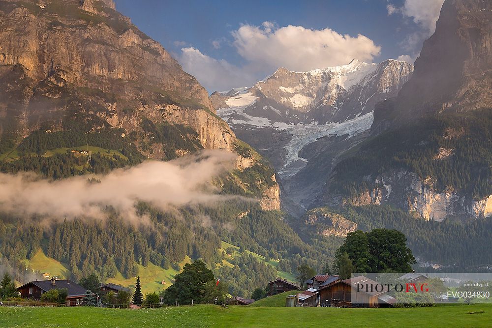 Sunset on Eiger and Fiescherhorn mountain, in foreground typical houses of Grindelwald, Berner Oberland, Switzerland, Europe