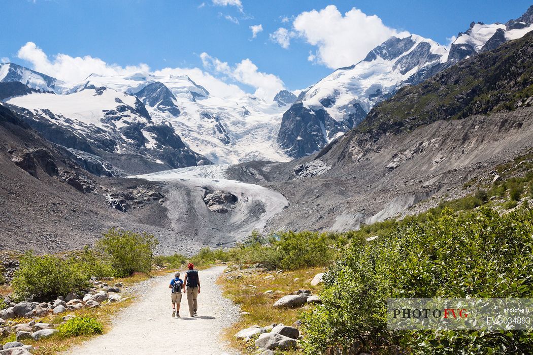 Hiking in Val Morteratsch valley, in the backgrond the glacier and the Bernina mountain range, Pontresina, Engadine, Canton of Grisons, Switzerland, Europe