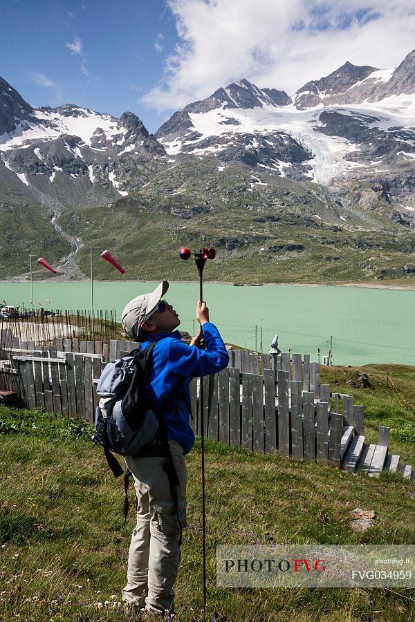 Child playing with the anemometer near Bernina Pass, in the background the Berninamountain group and the Lago Bianco lake, Engadin, Canton of Grisons, Switzerland, Europe
 