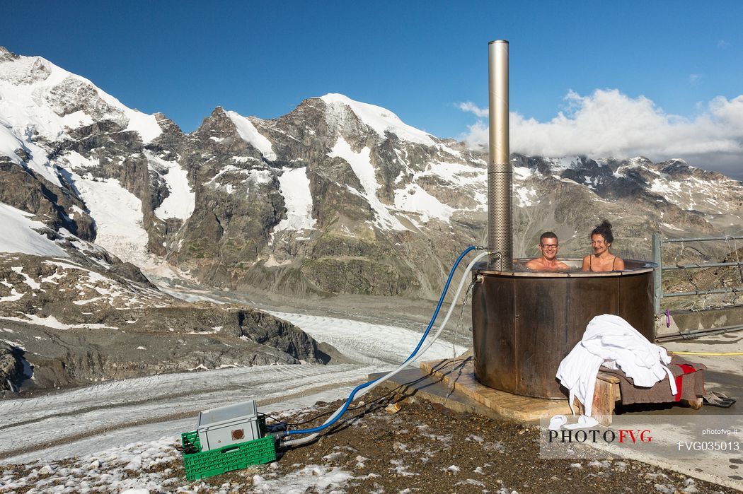 Tourists enjoing in the outdoor jacuzzi pool, in the background the Piz Bernina mountain range, Diavolezza Hut, Pontresina, Engadin, Canton of Grisons, Switzerland, Europe
 
