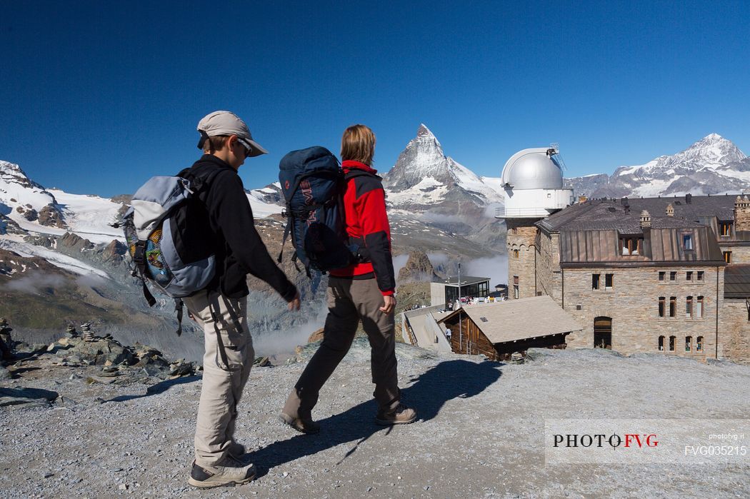 Hikers at the Gornergrat, in the background the Matterhorn or Cervino mount and the Kulm hotel with the astronomic observatory, Zermatt, Valais, Switzerland, Europe

