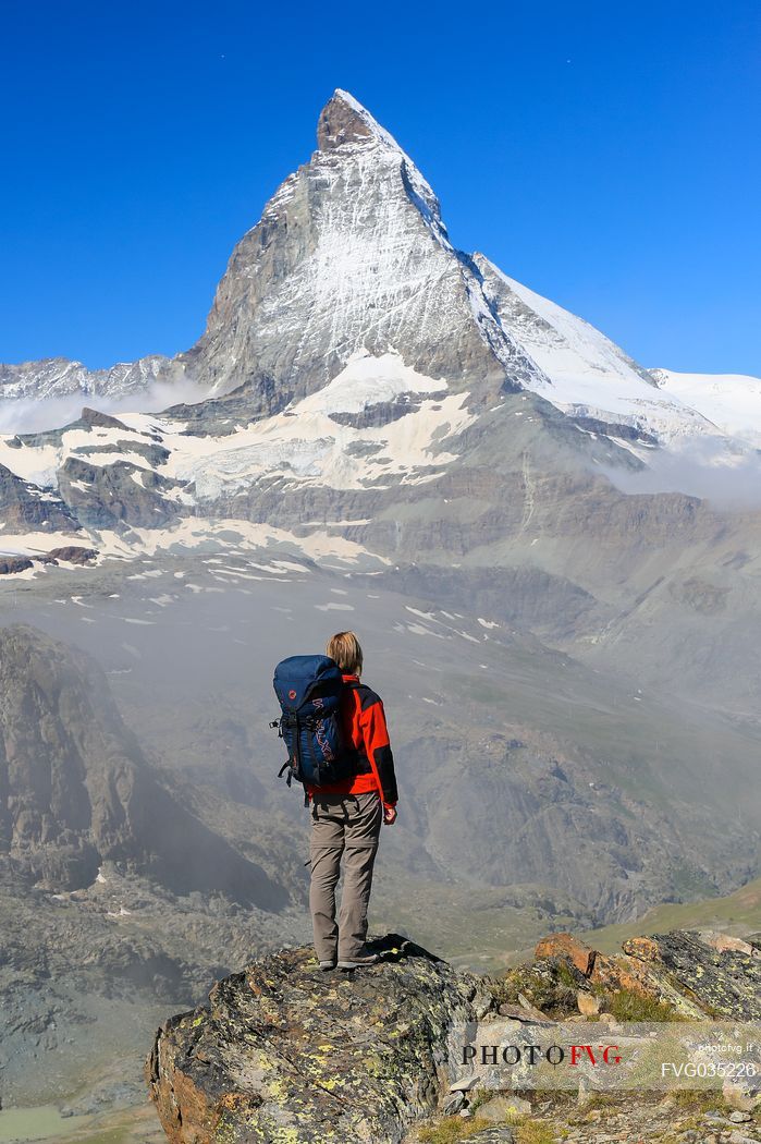 Hiker in the Gornergrat area admiring the Matterhorn or Cervino mount, Zermatt, Valais, Switzerland, Europe