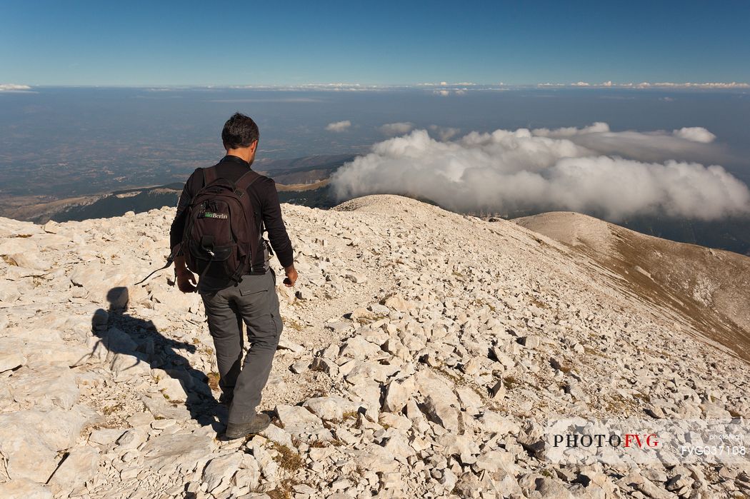 Hiker in the scree of Focalone mount in the Murelle amphitheater,in the background the Adriatic coast, Majella national park, Abruzzo, Italy, Europe