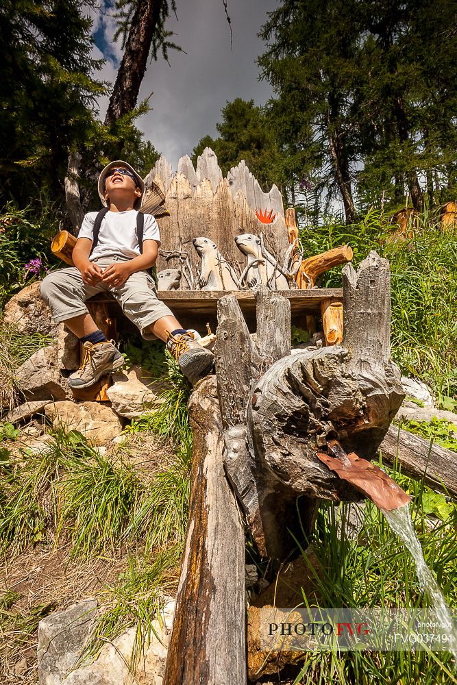 Young hiker rests on a wooden bench, Longiar, San Martino in Badia, Badia valley, dolomites, South Tyrol, Italy, Europe


