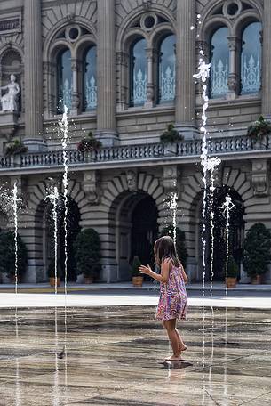 Child playing in the fountain in front of the parliament building in Bern, Switzerland, Europe