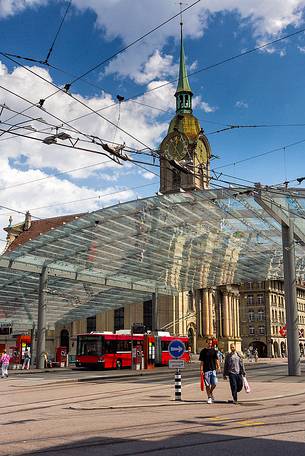 The modern covered tram and train station and in the background Holy Spirit Church or Heiliggeistkirche, Berne, Switzerland, Europe 