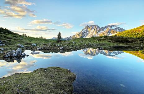 Sunrise on Mount Bivera, in foreground the reflections on alpine lake