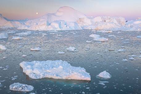 Moonlight over the icebergs of Kangerlua Fjord at dusk