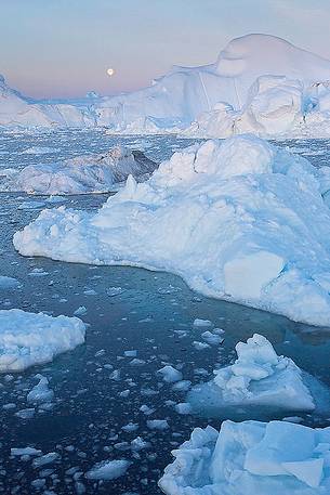 Moonlight over the icebergs of Kangerlua Fjord at dusk