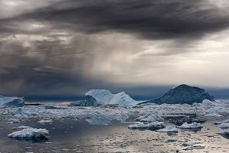 Dark clouds above blue icebergs in Disko Bay