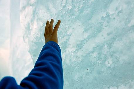 A child's hand caresses the frozen wall inside the Rhone glacier, Furka pass, Valais, Switzerland, Europe