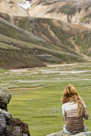 Young girl admires the multicoloured rhyolite mountain area of Landmannalaugar Young girl admires the multicoloured rhyolite mountain area of Landmannalaugar