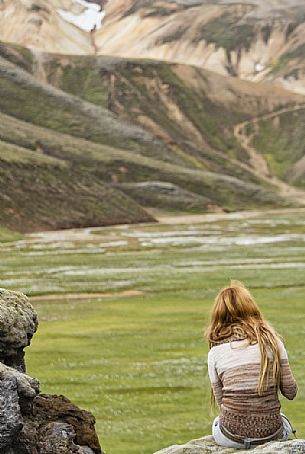 Young girl admires the multicoloured rhyolite mountain area of Landmannalaugar