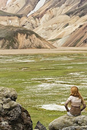 Young girl admires the multicoloured rhyolite mountain area of Landmannalaugar