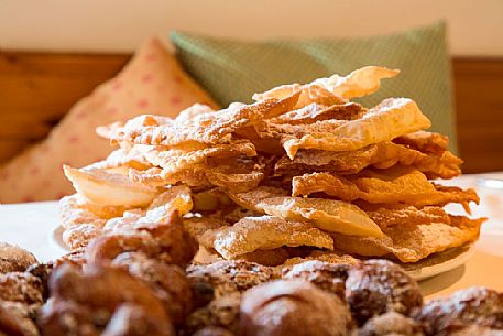 Crostoli and frittelle, typical cakes of the Carnival of Sauris one of the oldest and most characteristic of the Alps