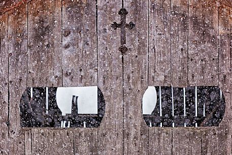 Under a snowfall a typical wooden building in alpine village of Sauris di Sotto