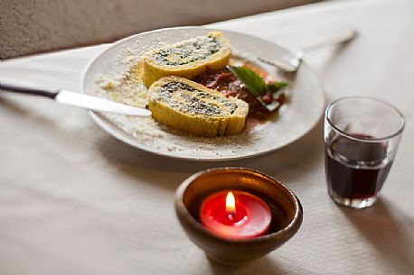 Roll of spinach and ricotta cheese with tomato sauce. Typical plate served in Malga Rinfreddo, Comelico, dolomites, Italy